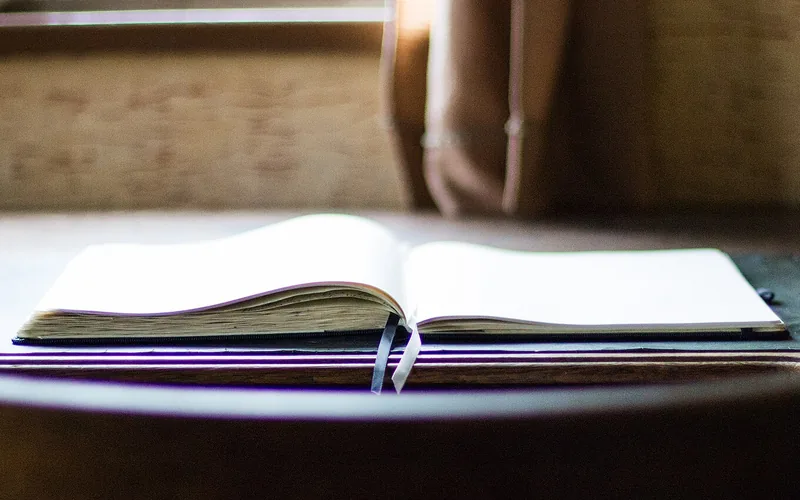 Aufgeschlagenes Notizbuch mit zwei Lesebändchen auf einem Holztisch